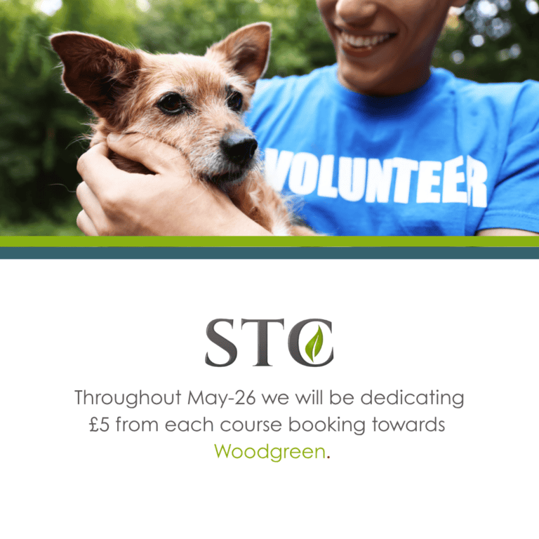 Volunteer in blue shirt holding a small brown dog with STC and Woodgreen donation message below